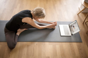 Woman 40+ practices yoga at home with notebook. Online yoga class. Woman 40+ practices yoga at home with notebook. Online yoga class.
